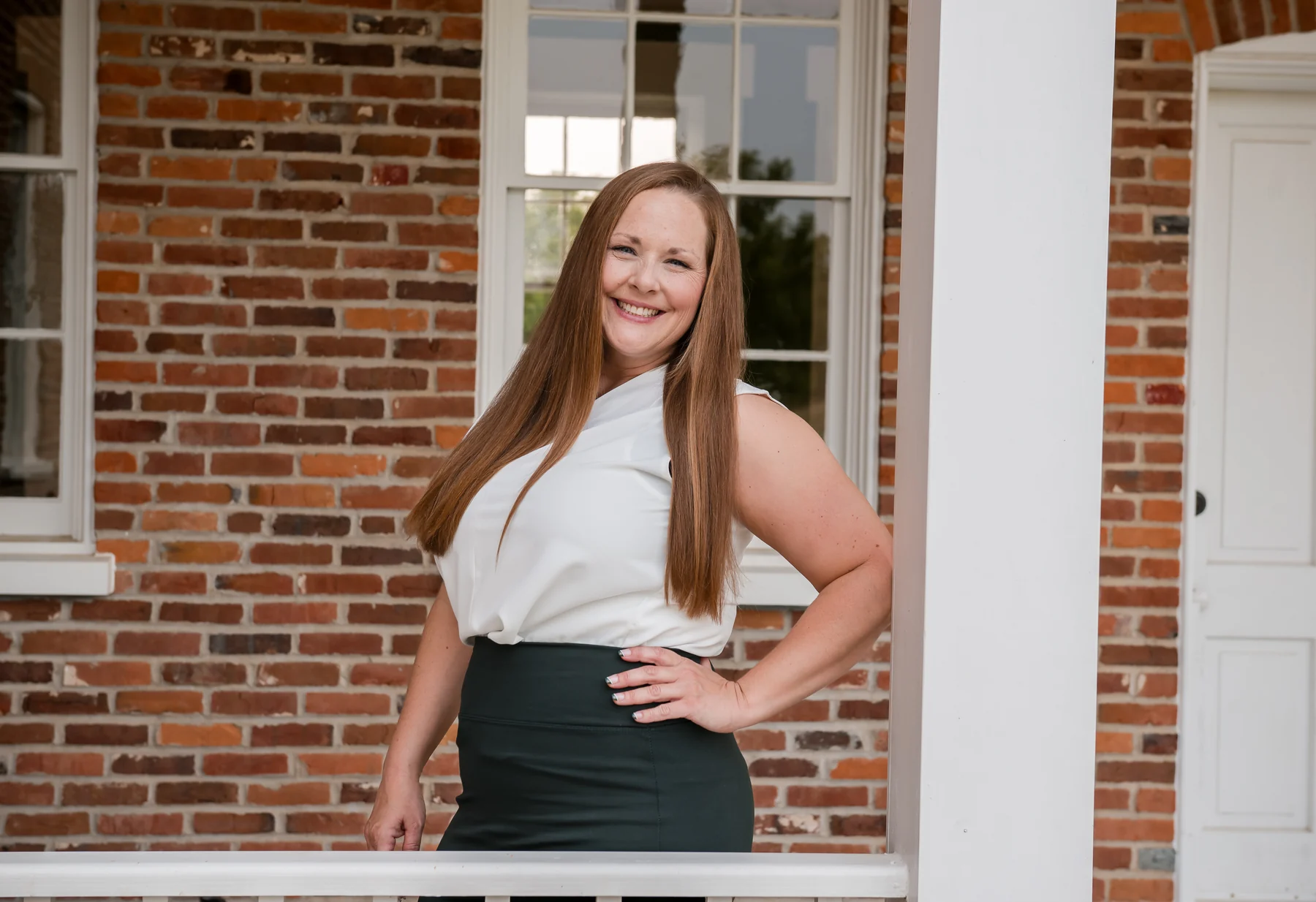 Jill, founder of KuhlBooks, smiling on a brick home's porch